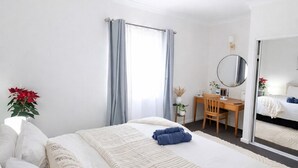 Ein Hotelzimmer mit einem großen Bett, einem Schreibtisch, einem Sessel und einem Spiegel.