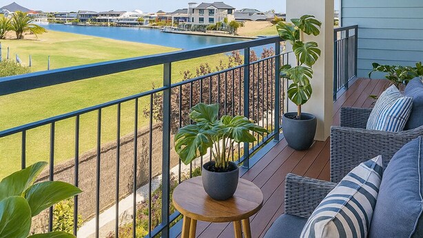 Ein Balkon mit Korbmöbeln, Blumentöpfen und Blick auf einen Golfplatz und Wasser.