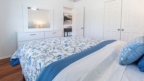 Un dormitorio con cama, cómoda, espejo y puerta.