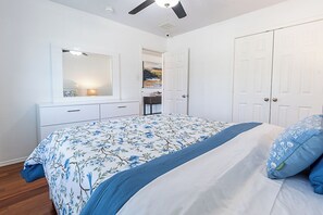A bedroom with a bed, a dresser, a mirror, and a door. - Charming 3-bedroom bungalow with AC in cozy Frisco (Frisco)