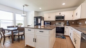 Una cocina moderna con armarios blancos, encimera de granito y electrodomésticos de acero inoxidable.