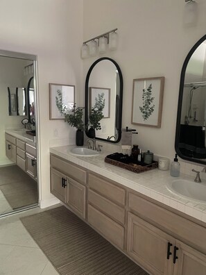 Un baño moderno con dos lavamanos, un espejo grande y una planta en maceta.