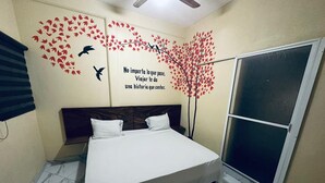 A bedroom with a bed, a sliding door, and a wall mural with a tree and birds. - Hotel NB aeropuerto (Puerto Vallarta)