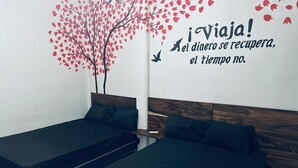 A room with two single beds, a wooden headboard, and a wall decal with a tree and birds. - Hotel NB aeropuerto (Puerto Vallarta)