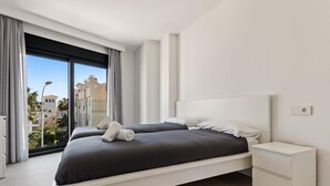 A modern bedroom with a large bed, a nightstand, and a view of the cityscape. - La Joya 1A. New apartment with Garage, 300 m from the beach (Torremolinos)
