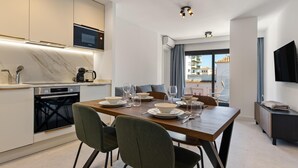 A modern kitchen with a built-in microwave, a dining area with a wooden table and chairs, and a TV mounted on the wall. - La Joya 1A. New apartment with Garage, 300 m from the beach (Torremolinos)