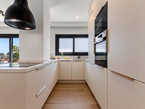 A modern kitchen with a central island, a black pendant light, and a window above the sink. - La Joya 1C. New apartment , 300 m from the beach (Torremolinos)