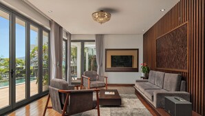 Een moderne woonkamer met een bank, fauteuils, een salontafel en een televisie.