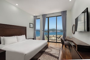 Una habitación de hotel con una cama grande, un escritorio, una silla y vista al mar.