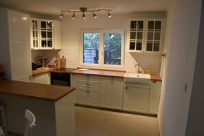 Eine Küche mit weißen Schränken, einer Holz Arbeitsplatte, einem Fenster mit Blick und einem integrierten Geschirrspüler.