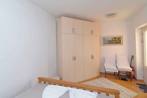 A bedroom with a bed, a wardrobe, a chair, a guitar, and a painting on the wall. - Holiday Apartment Villa Kaciol Veli Lošinj B4+2 A (Veli Lošinj)