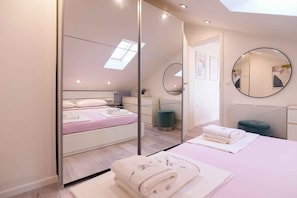 A modern bedroom with a bed, a round mirror, a bedside table, and a skylight. - Holiday flat centrally located with sea view (Mali Lošinj)