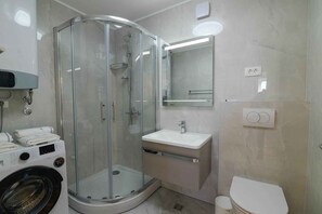 A modern bathroom with a glass-enclosed shower, a built-in sink, and a toilet. - Holiday flat centrally located with sea view (Mali Lošinj)