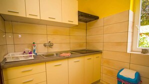Una cocina con armarios amarillos, un lavamanos de acero inoxidable y una ventana.