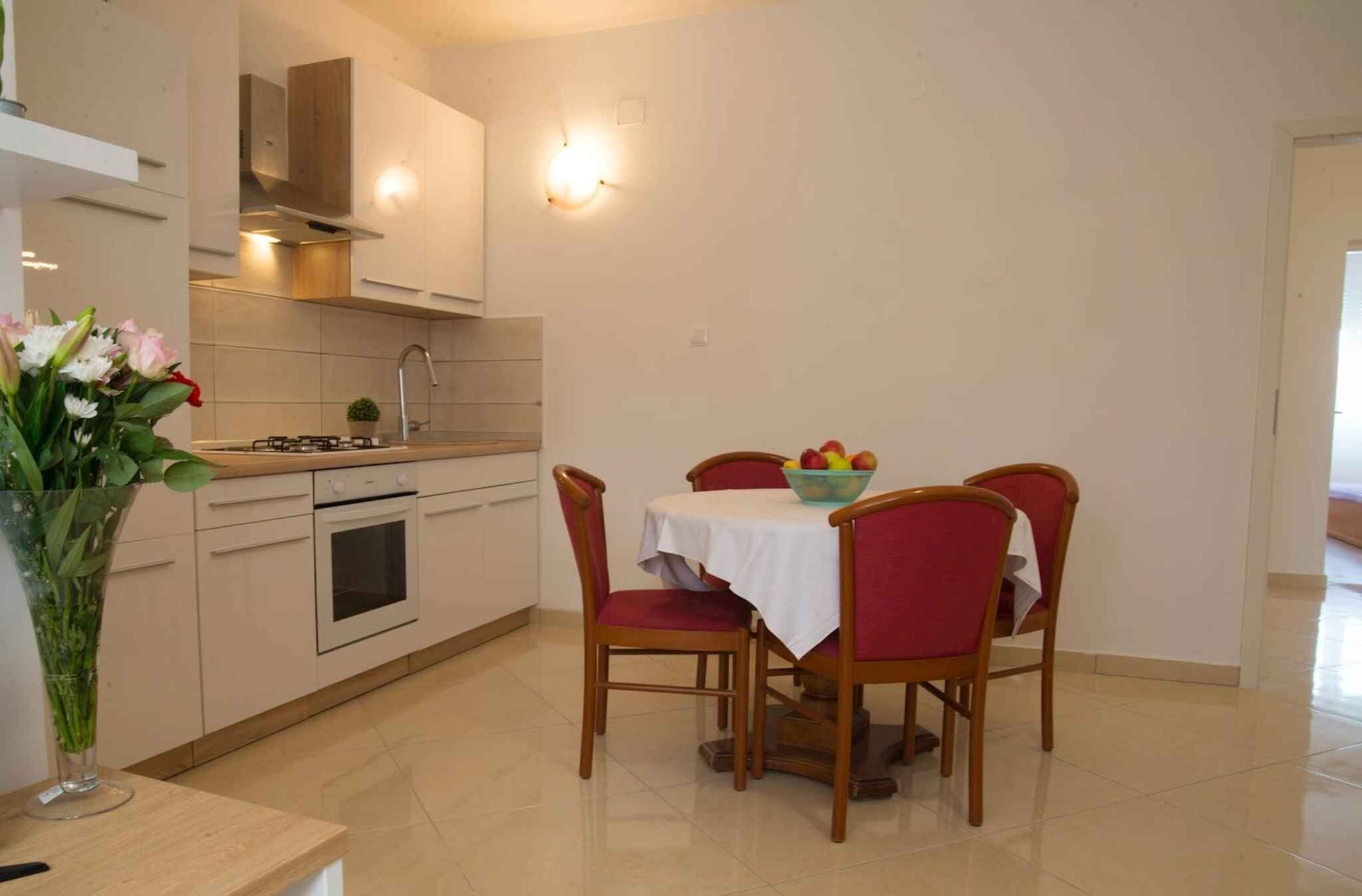 Une cuisine moderne avec une table et des chaises, un vase de fleurs et une cuisinière.