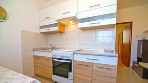 A compact kitchen with white cabinets, a built-in oven, and a stove. - Holiday Apartment Zeljka A2 (Mali Lošinj)