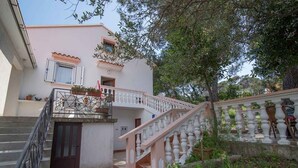 A two-story building with a staircase, a balcony, and a garden area. - Holiday Apartment Zeljka A2 (Mali Lošinj)