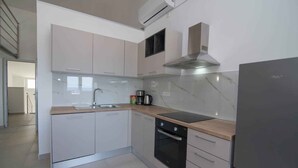 Eine moderne Küche mit weißen Schränken, einer Edelstahl-Dunstabzugshaube, einem Einbauofen und einem Kühlschrank.