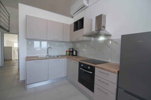 A modern kitchen with white cabinets, a stainless steel range hood, a built-in oven, and a refrigerator. - Holiday Apartment Deluxe apartment studio 1/4 (Mali Lošinj)
