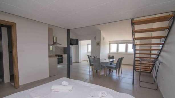 Ein modernes Hotelzimmer mit einem großen Bett, einem Essbereich und einer Treppe.