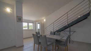 Ein moderner Essbereich mit großem Tisch und Stühlen, einer Treppe und einem Fenster für natürliches Licht.