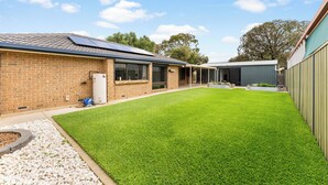 Ein Wohnhaus mit Backsteinfassade, einem gepflegten Rasen und einer Solaranlage auf dem Dach.
