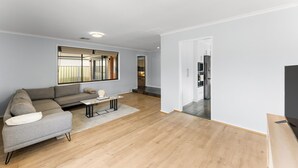 Ein modernes Wohnzimmer mit einer Eckcouch, einem Couchtisch und einem Flachbildfernseher.
