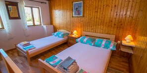 Une chambre avec deux lits simples, des murs en bois, une fenêtre et un tableau encadré accroché au mur.