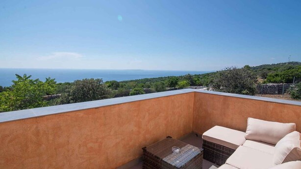 Ein Balkon mit Meerblick, einem kleinen Tisch und zwei Stühlen.