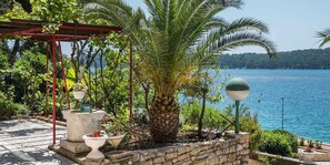Un mur de pierre, un palmier, une pergola et une étendue d’eau.