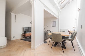 A modern living space with a dining area, a television, and a cozy seating area. - Blueground | Le Marais, view, nr Place des Vosges (Paris)