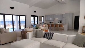 En moderne stue med en stor modulsofa, et sofabord og udsigt til havet.