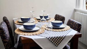 A dining table with blue bowls, wine glasses, and a woven placemat. - Host Stay The Stables Apartment 1 (Saltburn-by-the-Sea)