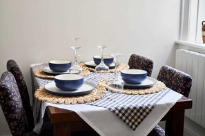 Uma mesa de jantar com tigelas azuis, copos de vinho e um jogo americano trançado.