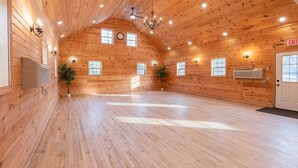 A spacious room with wooden walls, a chandelier, and multiple windows. - King Room Near Hiking White Mountains (Bethlehem)