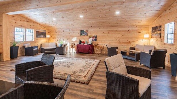 A log cabin interior with wicker furniture, a central dining table, and artwork on the walls. - King Room Near Hiking White Mountains (Bethlehem)