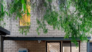 Un edificio de ladrillo con cercado metálico, una puerta y una ventana.