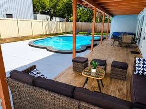 Un jardin avec une piscine, du mobilier d’extérieur et une pergola.