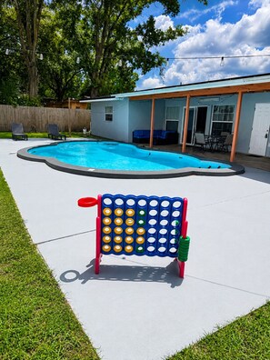 A backyard with a swimming pool, a patio area, and a game table. - Perfect 4-bedroom house with AC in enchanting Tampa (Tampa)