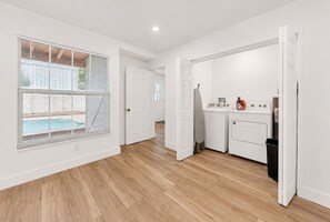 A clean, modern kitchen with white appliances, a wooden floor, and a view of a pool through the window. - Perfect 4-bedroom house with AC in enchanting Tampa (Tampa)