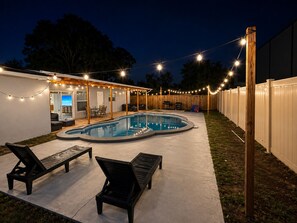 A backyard with a swimming pool, outdoor seating, and string lights. - Perfect 4-bedroom house with AC in enchanting Tampa (Tampa)