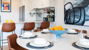 Et moderne spiseområde med et rundt bord, brune læderstole og en blå skål med appelsiner.