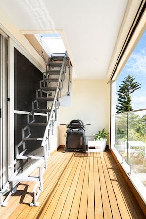 A wooden deck with a metal staircase, a black motorcycle, and a potted plant. - Views from Rooftop Deck - Central OG - Ocean Luxe (Ocean Grove)
