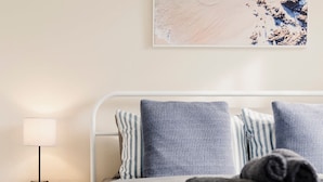 Un lit avec une literie à rayures, une serviette enroulée et une table de chevet avec une lampe.