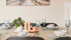 Une table à manger dressée avec des assiettes, des bols, des verres et un arrangement floral en guise de décoration centrale.