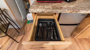 A kitchen with a drawer containing utensils, a microwave, and a refrigerator.