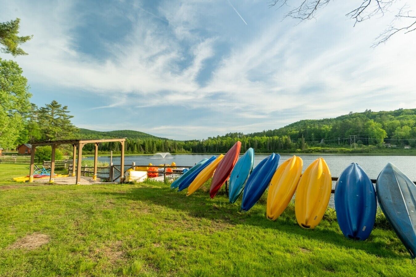 A lakeside setting with a gazebo and a row of kayaks.