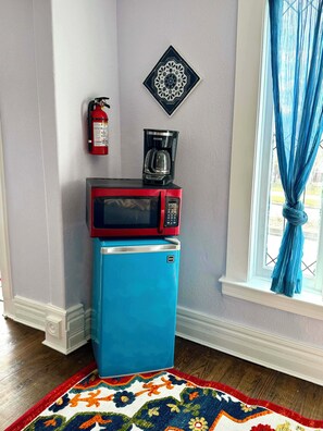 A compact kitchenette with a red microwave, a blue refrigerator, a coffee maker, a fire extinguisher, and a decorative wall piece. - Yellow Cozy 1-bedroom house in Denver (Denver)