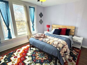 A bedroom with a bed, nightstand, lamp, and a window with curtains. - Yellow Cozy 1-bedroom house in Denver (Denver)