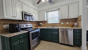 A kitchen with white cabinets, a stainless steel microwave, a stove, and a dishwasher.